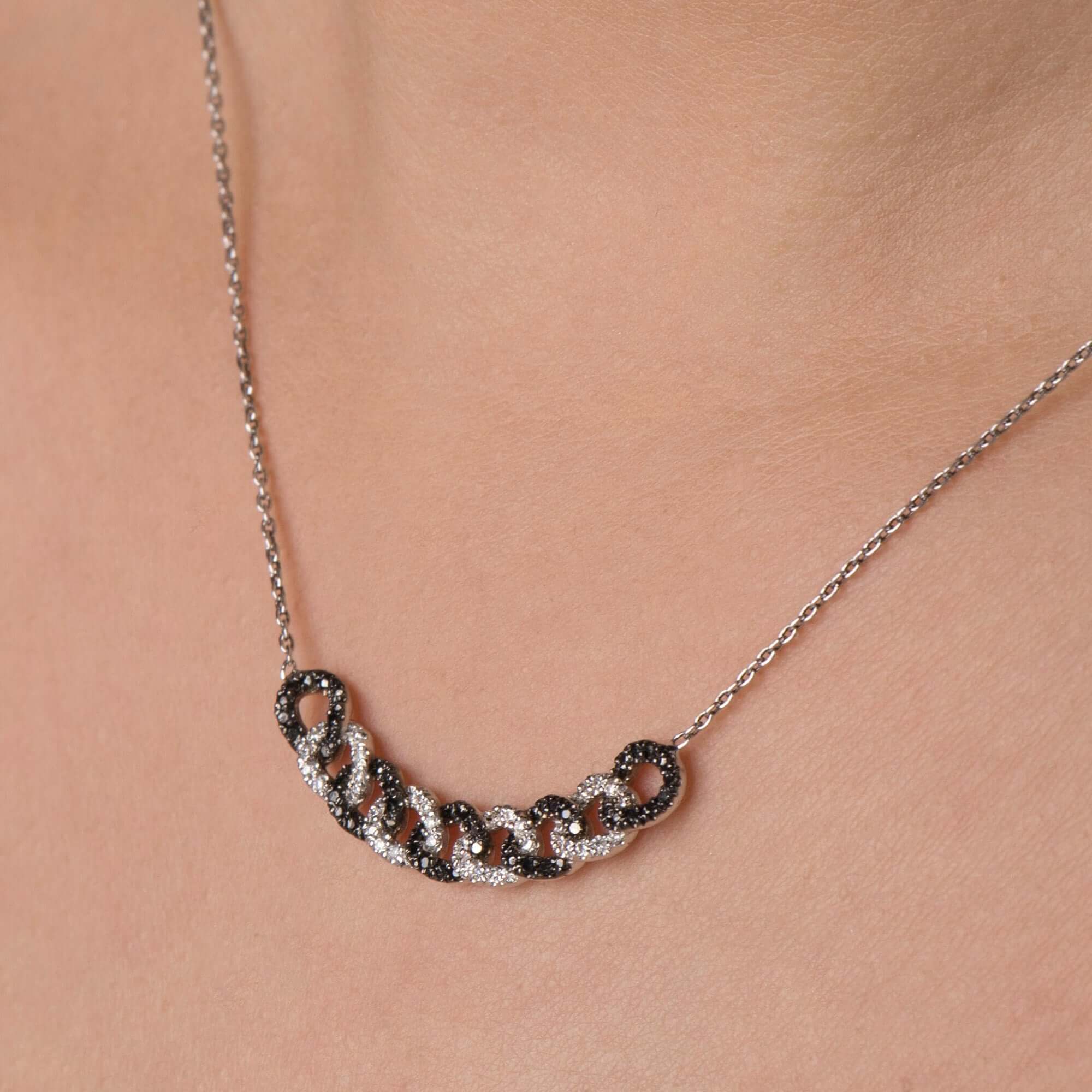 Necklace with interlocking rings on a person's neck against a neutral background