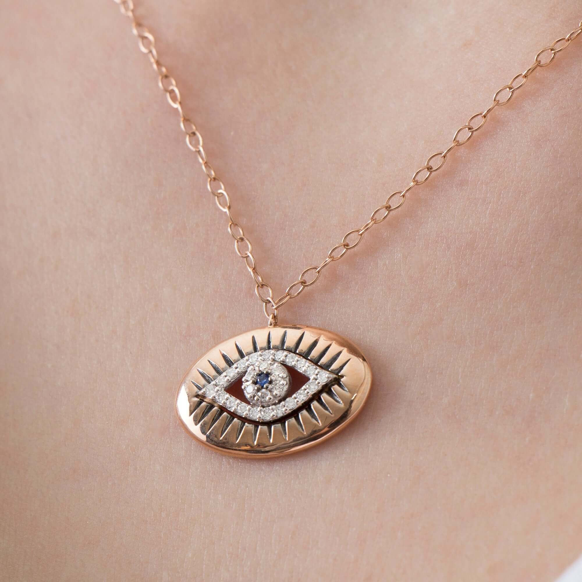 Rose gold necklace with an eye-shaped pendant on a person's neck