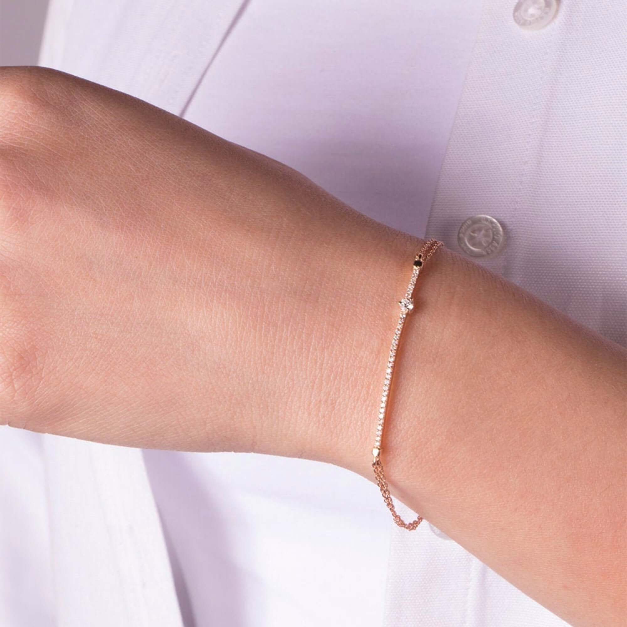 Rose gold bracelet on a person's wrist with a light background