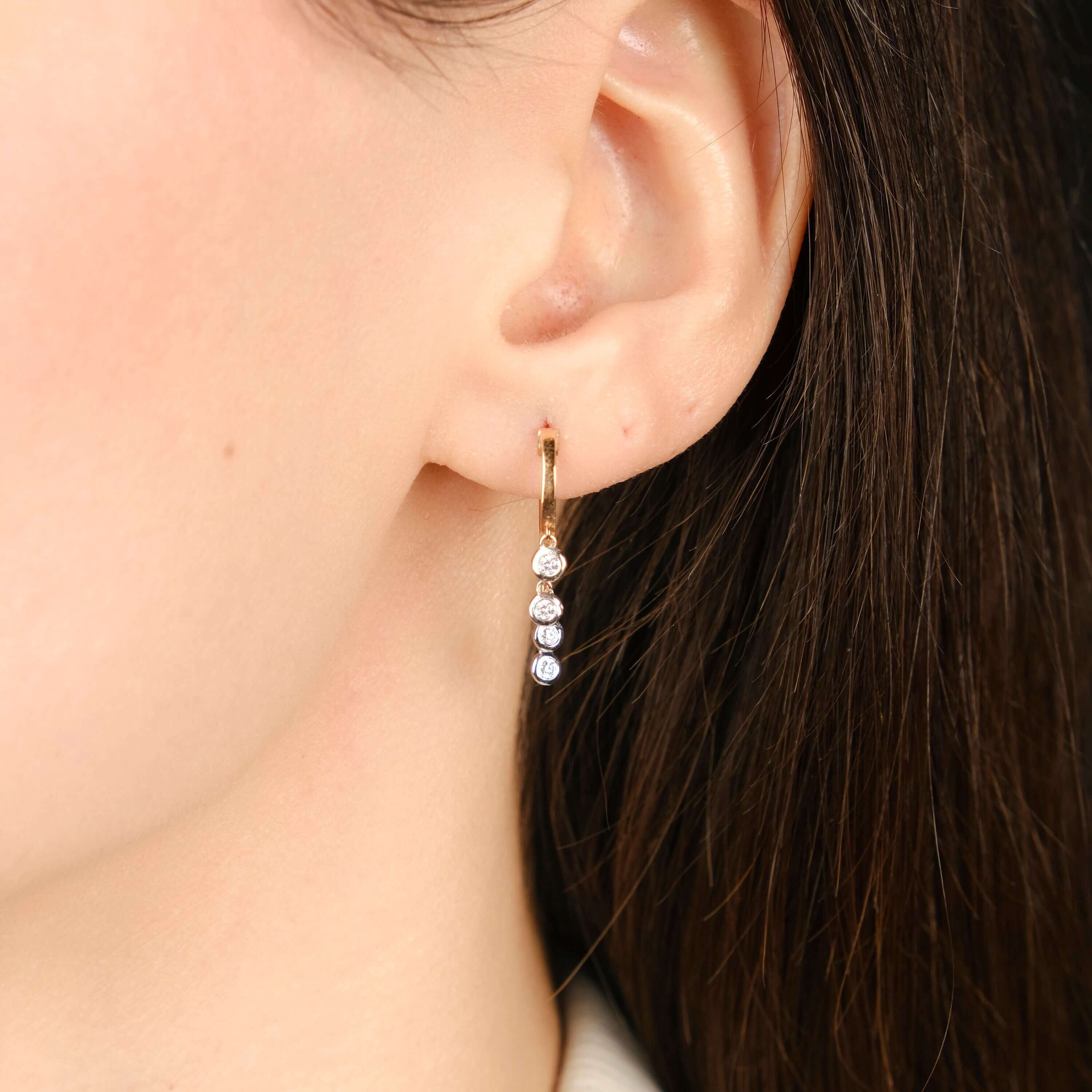 model minimal pırlanta sallantılı halka küpeyi takıyor