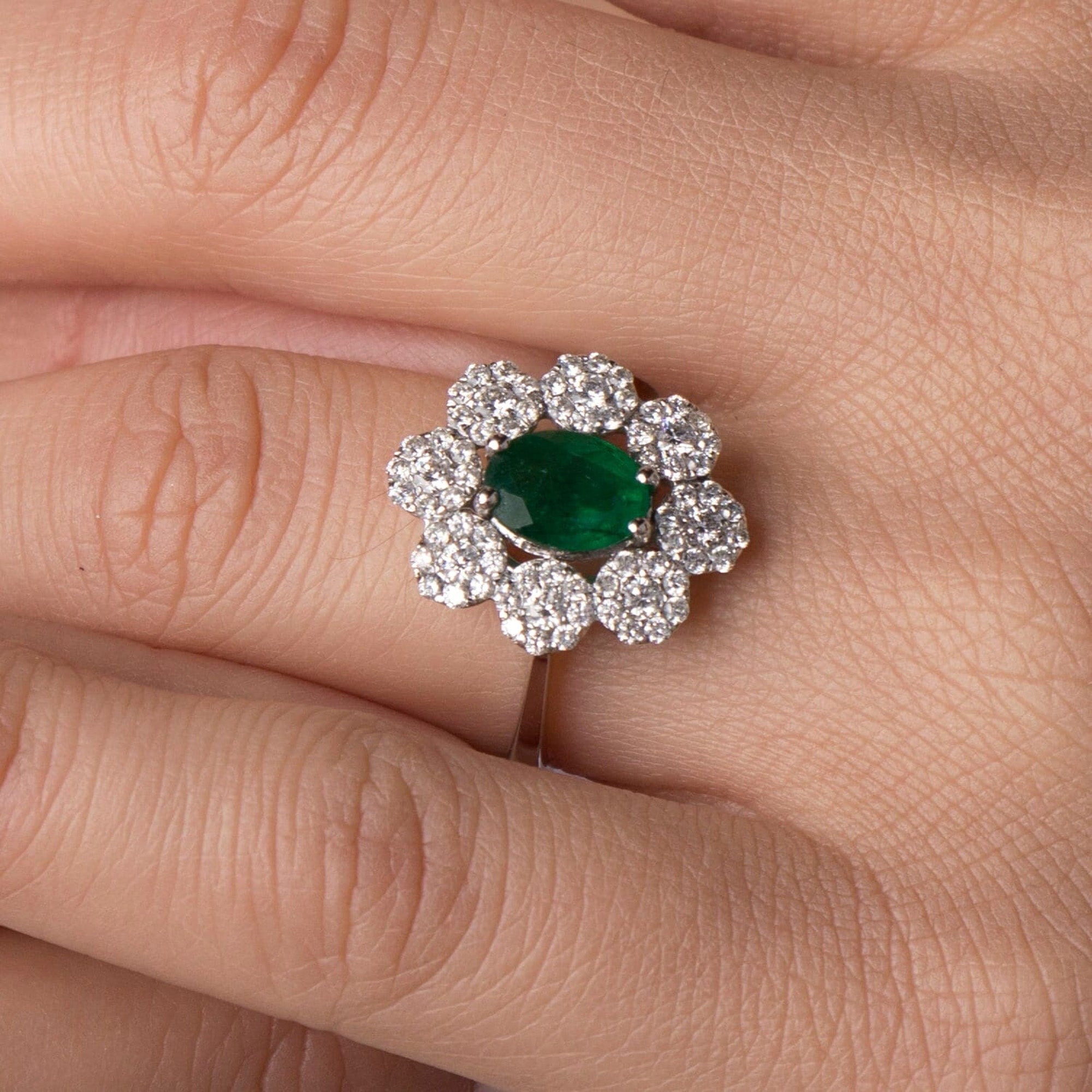 Ring with emerald and diamonds on a finger